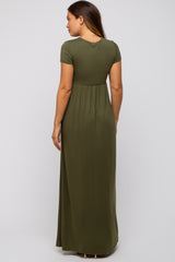 woman wearing a dark green short sleeve maternity maxi dress, showing the back view and a baby bump