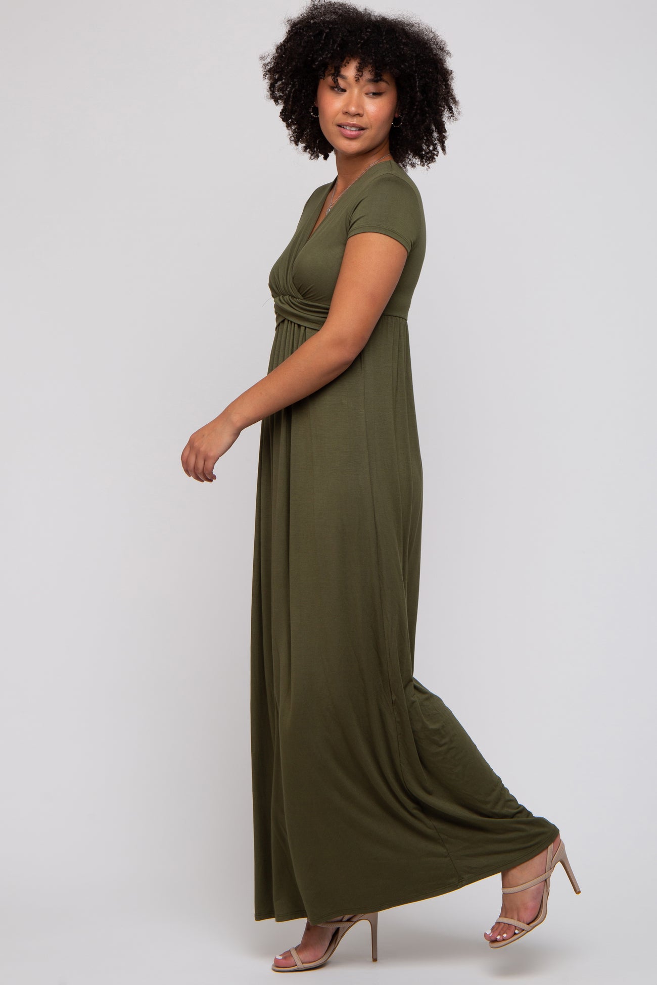 woman wearing a short sleeve olive green maxi dress, standing sideways with a relaxed pose