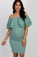 woman wearing a mint green off-shoulder ruffled maternity dress with a visible baby bump