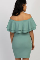 woman wearing a green off-the-shoulder maternity dress with ruffles and showing her baby bump