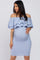 woman wearing a light blue off-the-shoulder maternity dress with ruffle details and showing her baby bump