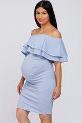 woman wearing a light blue off-the-shoulder maternity dress with layered ruffles and showing her baby bump