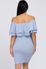 woman wearing a light blue off-the-shoulder maternity dress with layered ruffle details, showing a smooth fit