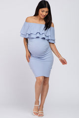 woman wearing a light blue off-the-shoulder maternity dress with ruffles, showcasing her baby bump