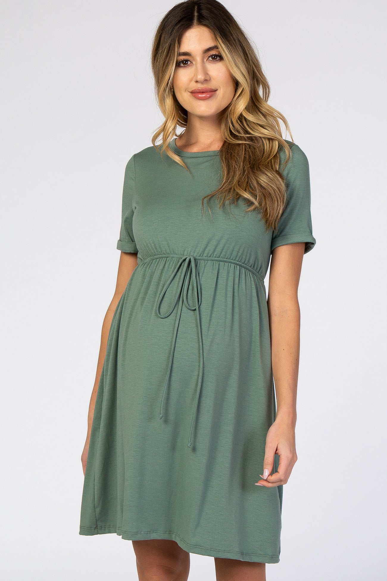 woman wearing a sage green short sleeve maternity dress with a drawstring waist and flowing skirt