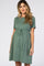 woman wearing a sage green short sleeve maternity dress with a drawstring waist and flowing skirt