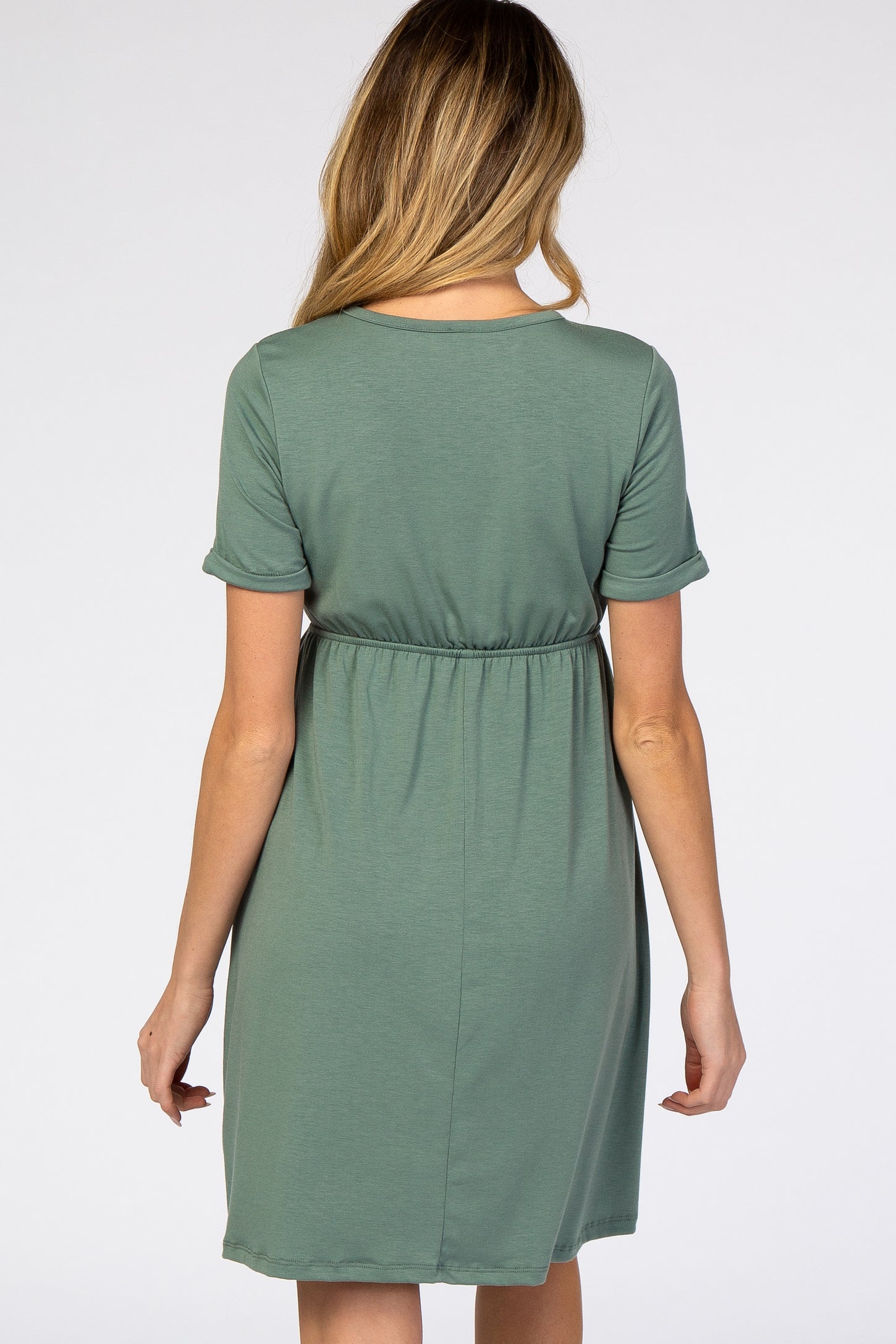 woman wearing a green short sleeve maternity dress with an elastic waistband and a relaxed fit