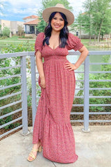 woman wearing a pink floral maxi dress with puff sleeves and a fitted waist, styled with a wide-brimmed hat