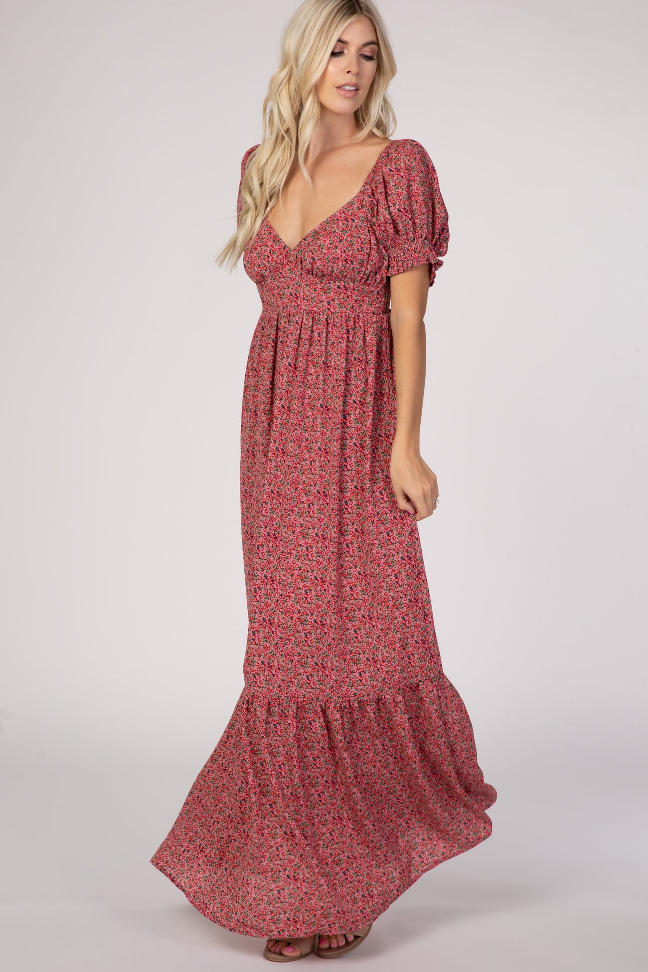woman wearing a pink floral maxi dress with short puff sleeves and a tiered skirt