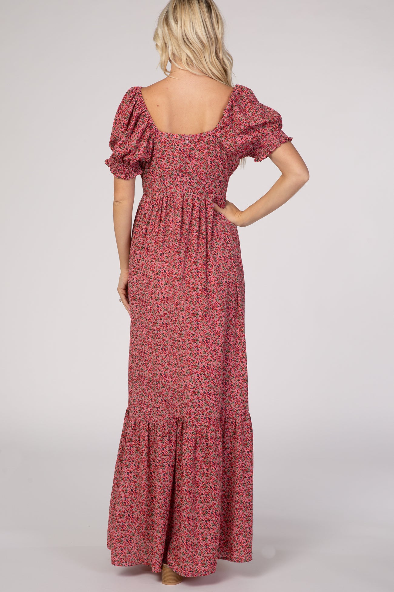 Back view of a blonde woman wearing a pink floral puff sleeve maxi dress with a tiered skirt
