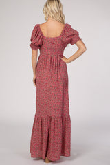 Back view of a blonde woman wearing a pink floral puff sleeve maxi dress with a tiered skirt