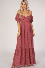 woman wearing a pink floral off-the-shoulder maxi dress with puff sleeves and a tiered skirt