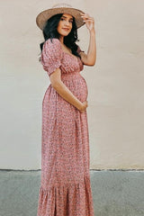 woman wearing a pink floral maternity maxi dress with puff sleeves and holding her baby bump