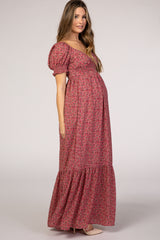 woman wearing a pink floral maternity maxi dress with puff sleeves and a gathered skirt, showcasing her baby bump