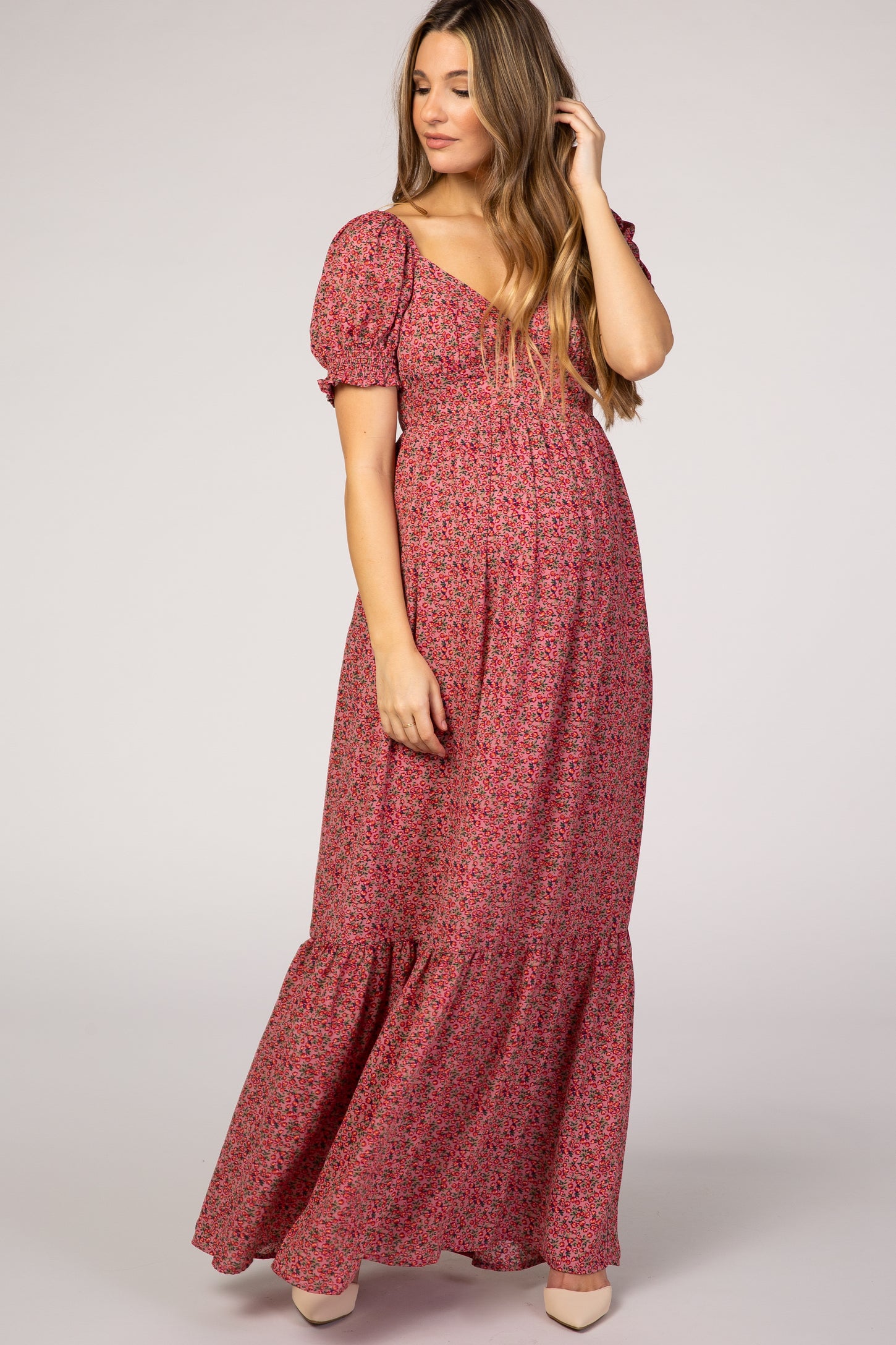 woman wearing a floral print maternity maxi dress with puff sleeves and a tiered hem, highlighting her baby bump