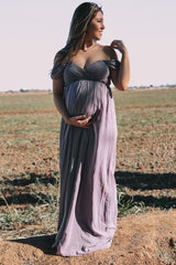 woman wearing a lavender off-the-shoulder maternity gown and holding her baby bump in a field
