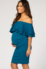 woman wearing a teal off-the-shoulder maternity dress with ruffle details and a visible baby bump