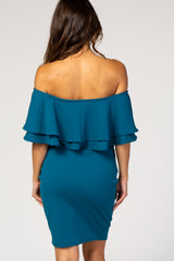 woman wearing a teal off-the-shoulder maternity dress with a ruffled overlay and fitted design