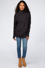 woman wearing charcoal grey oversized turtleneck sweater with blue jeans and tan ankle boots