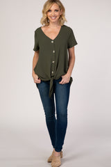 woman wearing an olive green short sleeve button-up top with a knot detail, paired with blue skinny jeans and beige heels