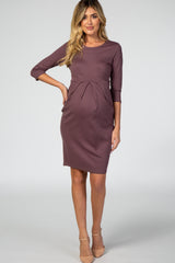 woman wearing a mauve maternity dress with three-quarter sleeves and a pleated detail over her baby bump