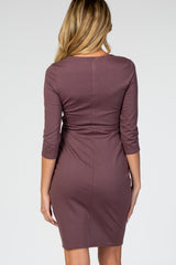 woman wearing a mauve fitted maternity dress with three-quarter sleeves, showing a baby bump from the back
