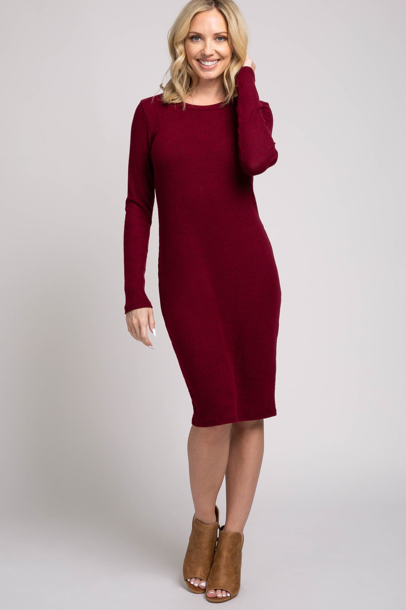 woman wearing a burgundy long sleeve fitted dress and tan heeled ankle boots