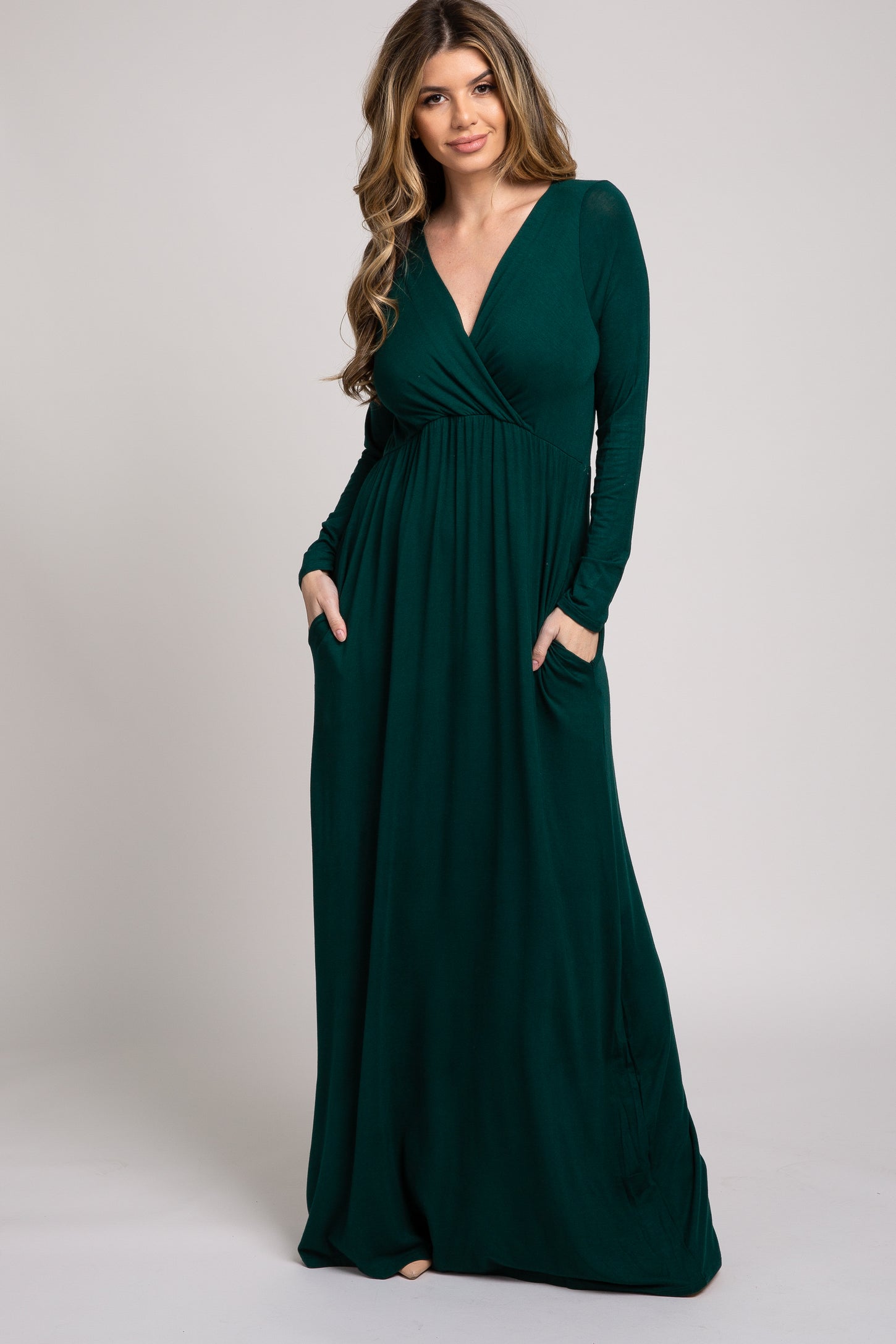 woman wearing a long sleeve deep green maxi dress with a wrap-style top and pockets