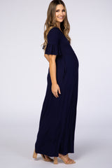Pregnant woman wearing a navy blue short sleeve maternity maxi dress with ruffle sleeves and tan heels