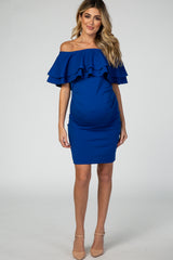 woman wearing a royal blue off-shoulder maternity dress with ruffle detailing and visible baby bump