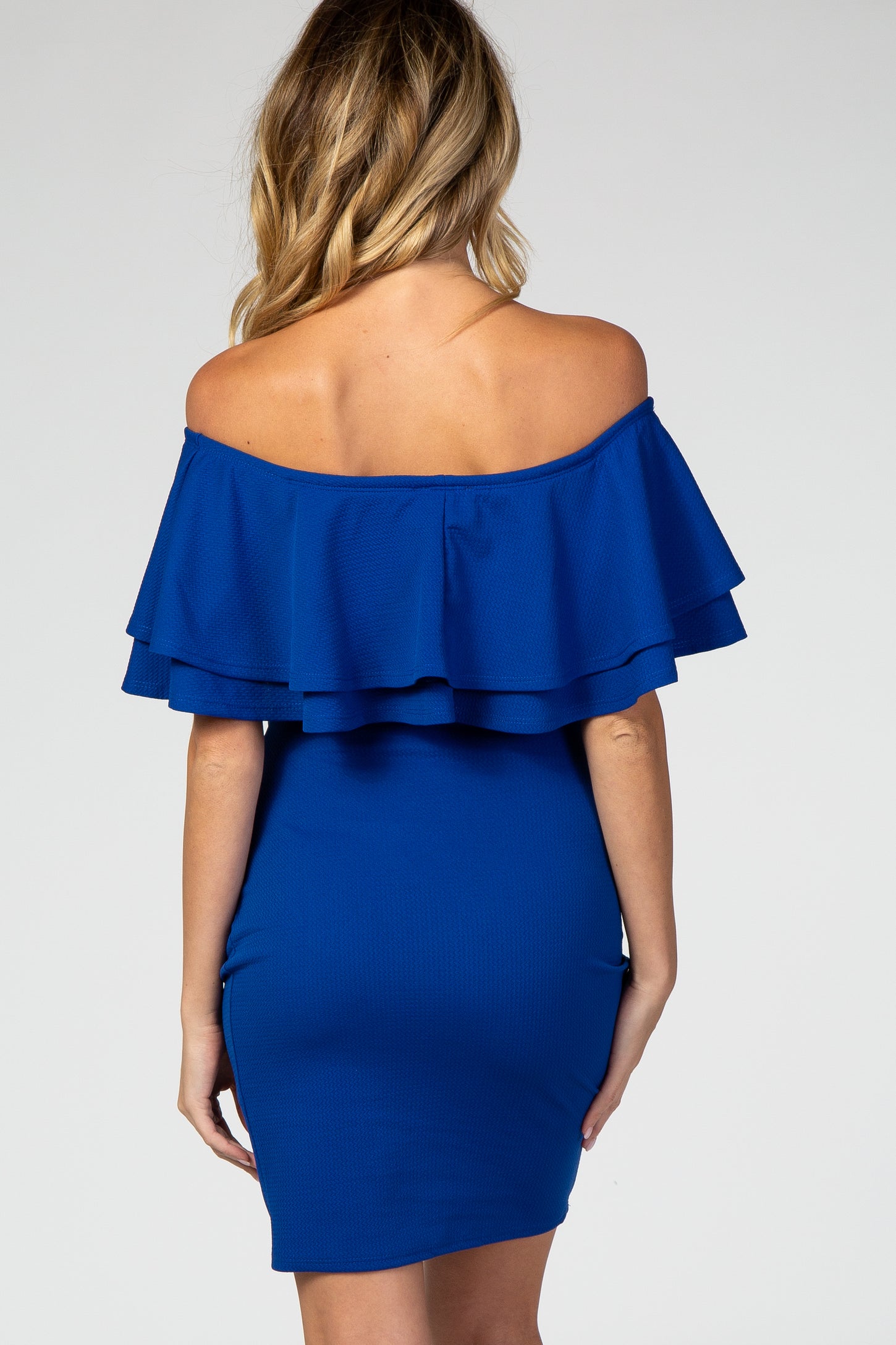 woman wearing a royal blue off-the-shoulder maternity dress with layered ruffle details on the sleeves