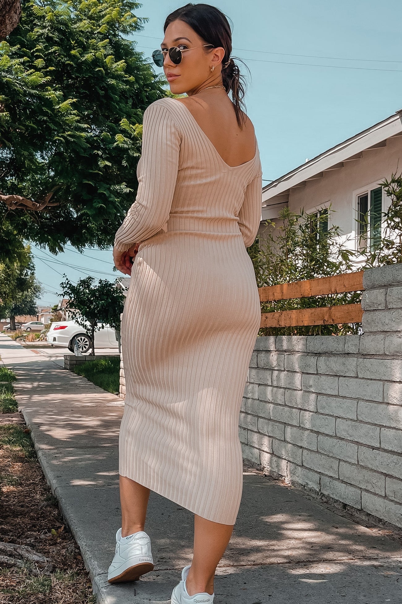 woman wearing a light beige ribbed knit midi dress with a low back and paired with white sneakers