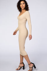 woman wearing a beige ribbed long sleeve midi dress with a fitted silhouette and v-neckline