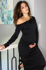 woman wearing a black off-shoulder maternity dress and holding her baby bump