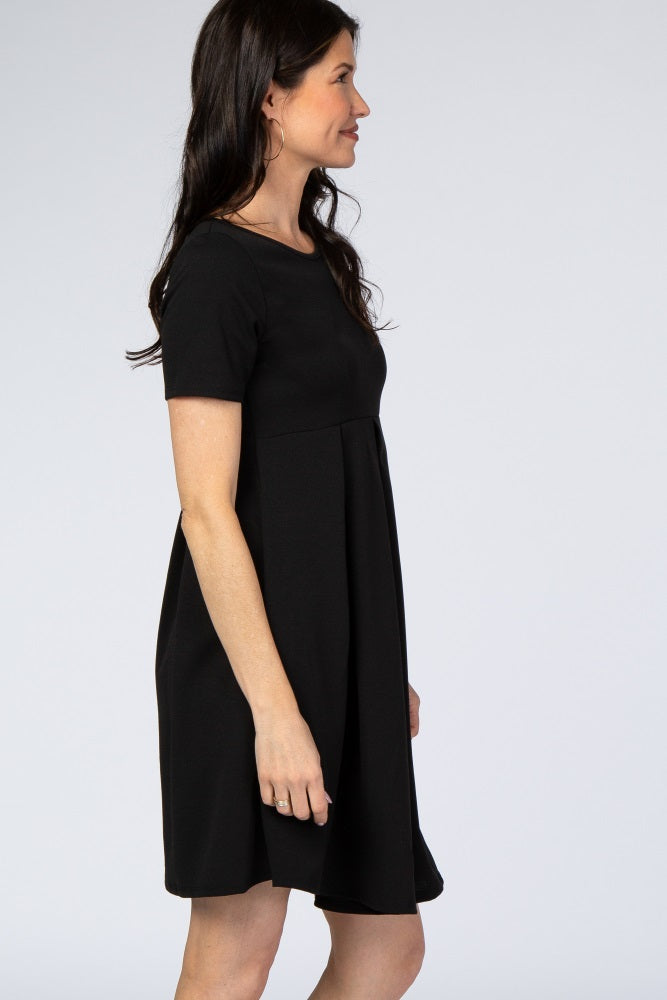 woman wearing a short sleeve black maternity dress with pleated skirt shown from a side profile view