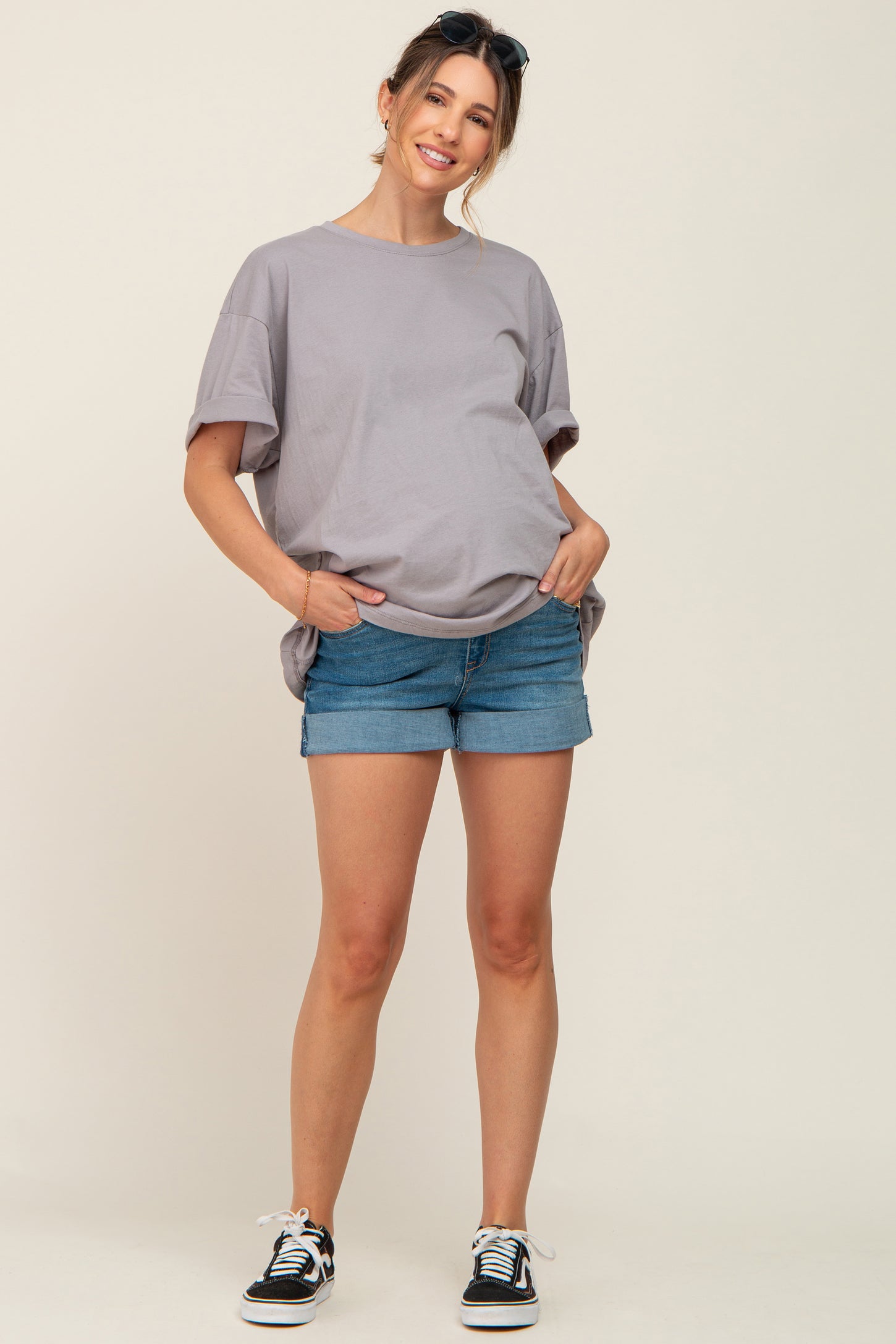 woman wearing a light gray oversized maternity t-shirt and denim shorts with a visible baby bump