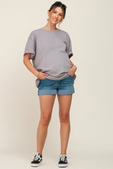 woman wearing a light gray oversized maternity t-shirt and denim shorts with a visible baby bump