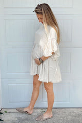woman wearing a light beige short sleeve maternity dress with lace details and a visible baby bump