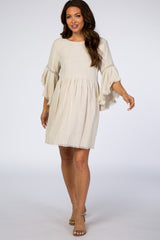 woman wearing a cream maternity dress with wide sleeves and fringe hemline, walking gracefully