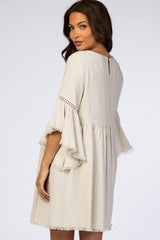 woman wearing a beige maternity dress with bell sleeves and a keyhole back detail