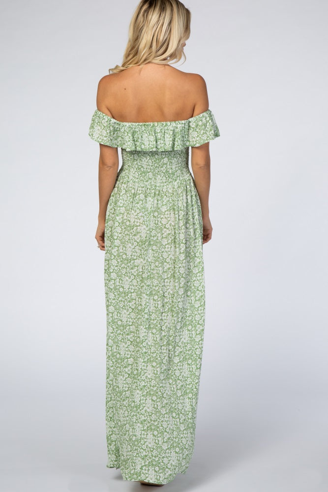 woman wearing a green floral off-the-shoulder maxi dress, showing the back view with a fitted bodice and flowing skirt