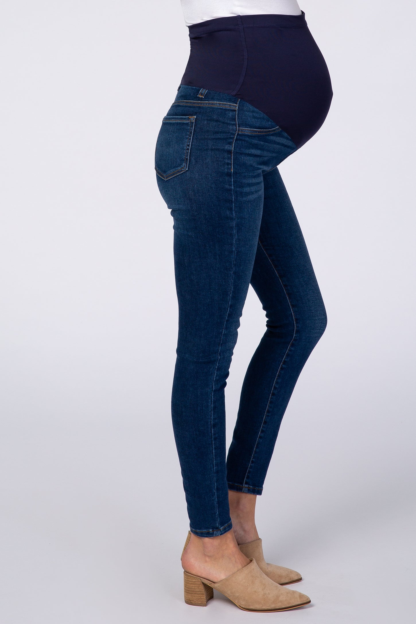 woman wearing dark blue maternity skinny jeans with a high waistband, showcasing a baby bump