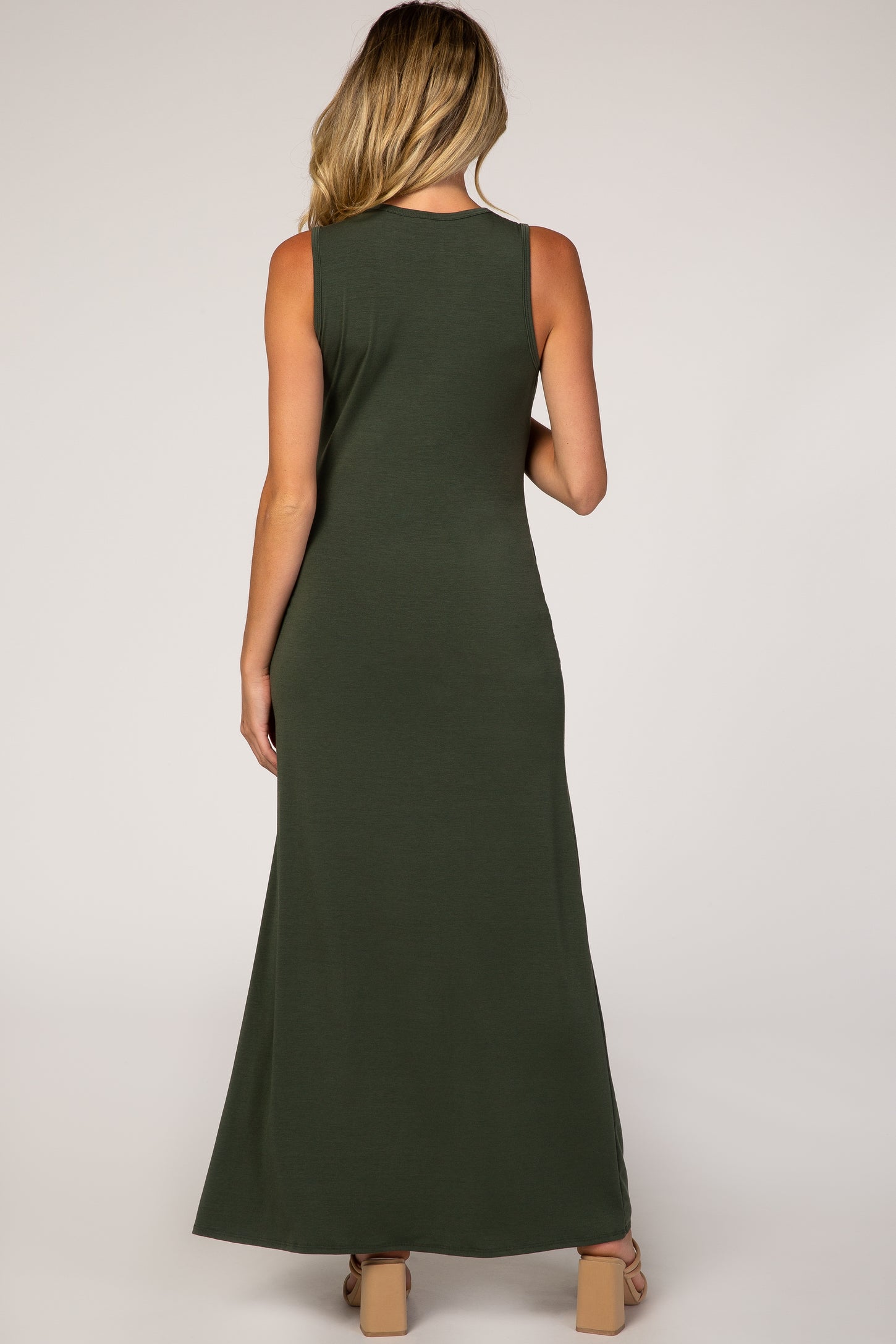 back view of a woman wearing a sleeveless olive green maxi dress and tan block heel sandals