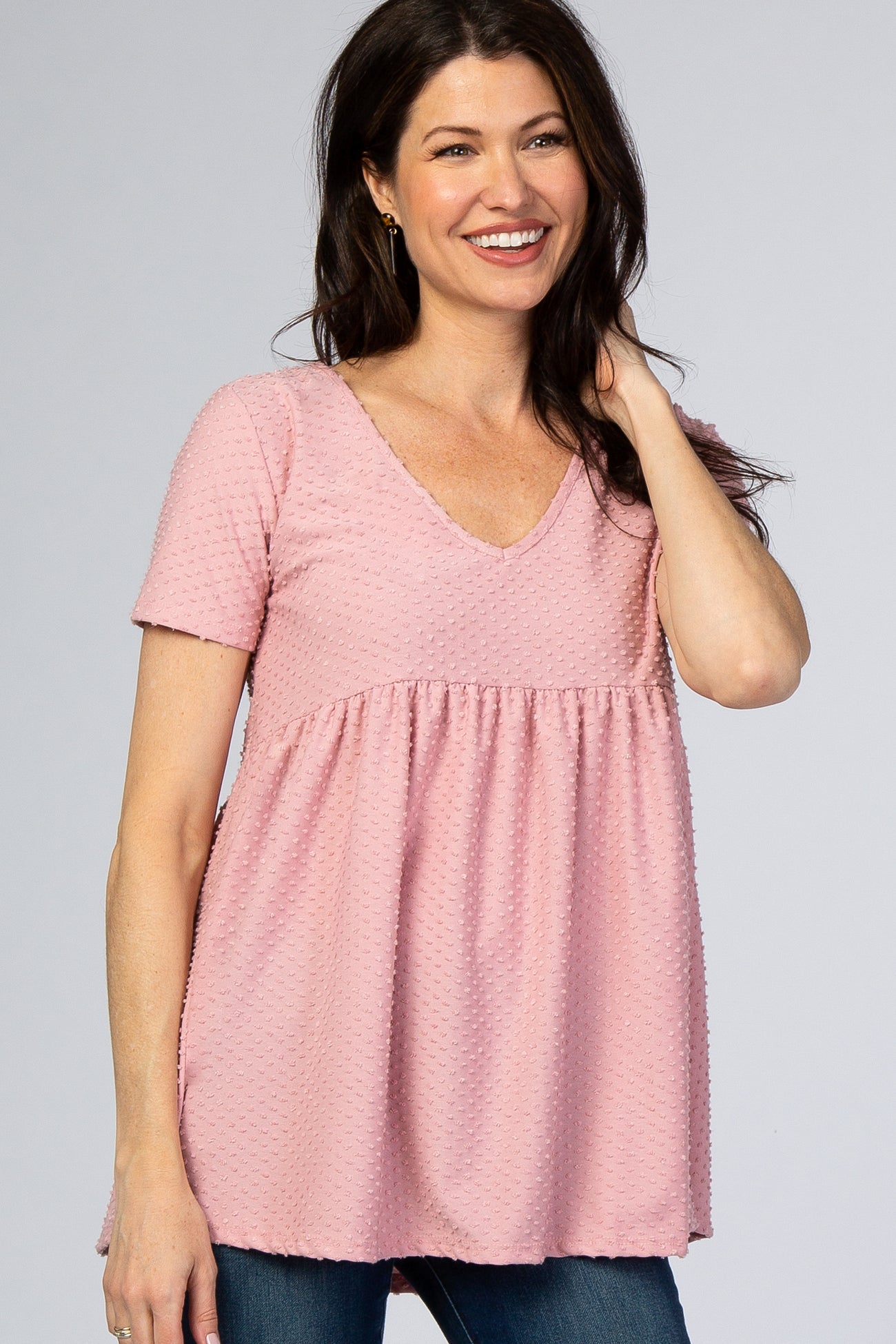 smiling woman wearing a pink short sleeve swiss dot v-neck maternity top