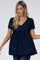 blonde woman wearing a navy blue short sleeve swiss dot maternity tunic top with a v-neckline