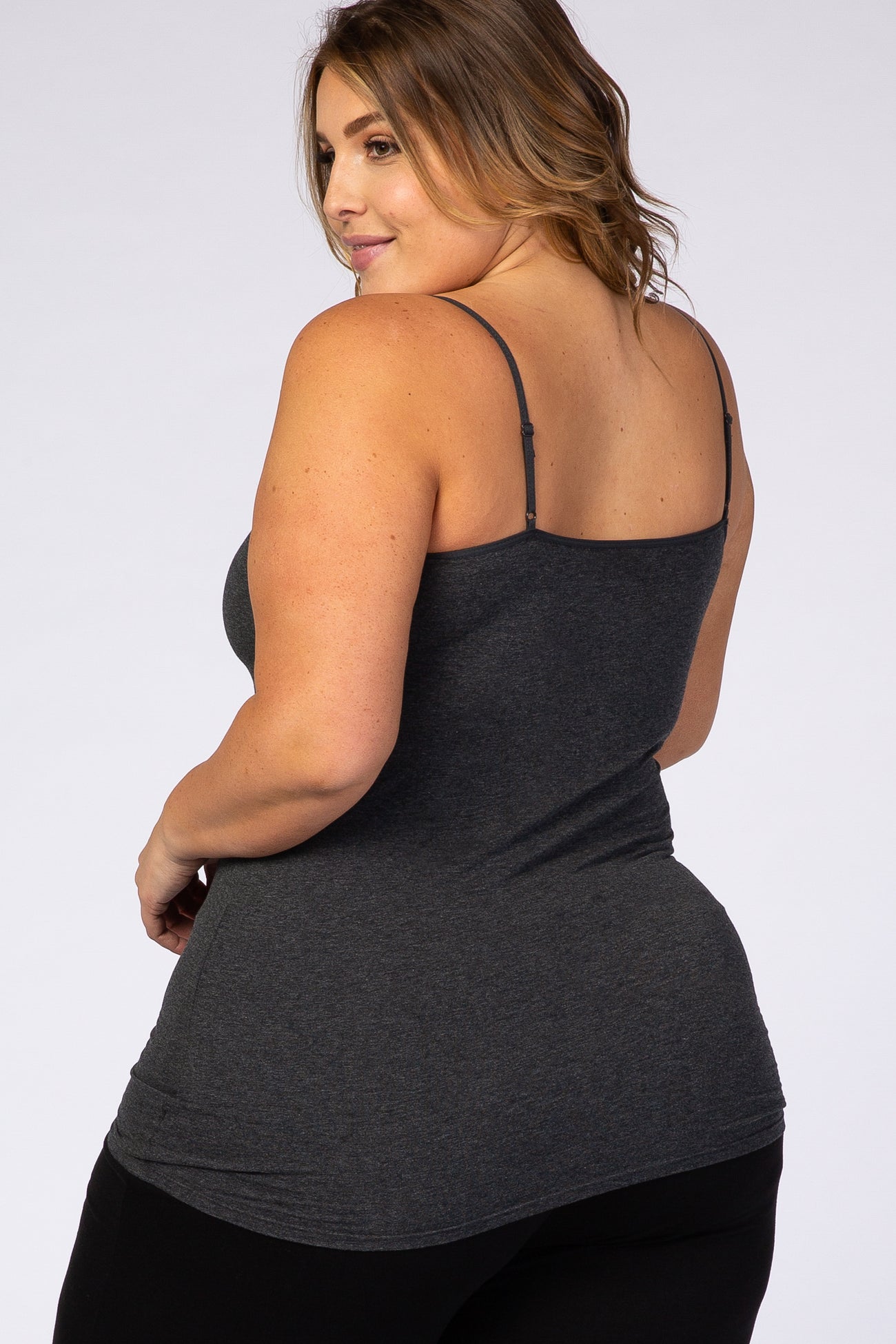 woman wearing a dark gray plus size camisole with thin straps, looking over her shoulder