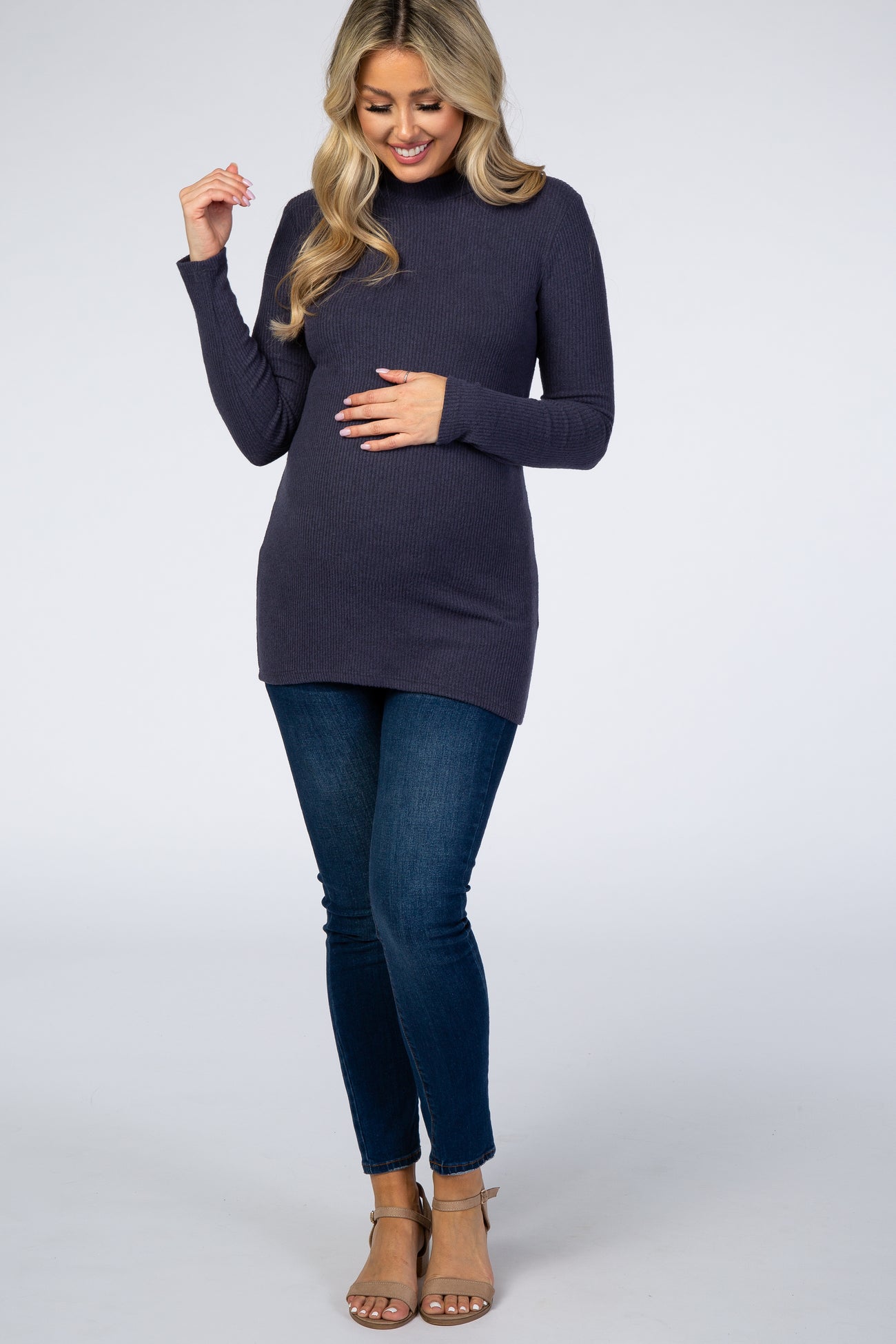 Pregnant woman in navy ribbed maternity tunic top and blue skinny jeans with tan heels