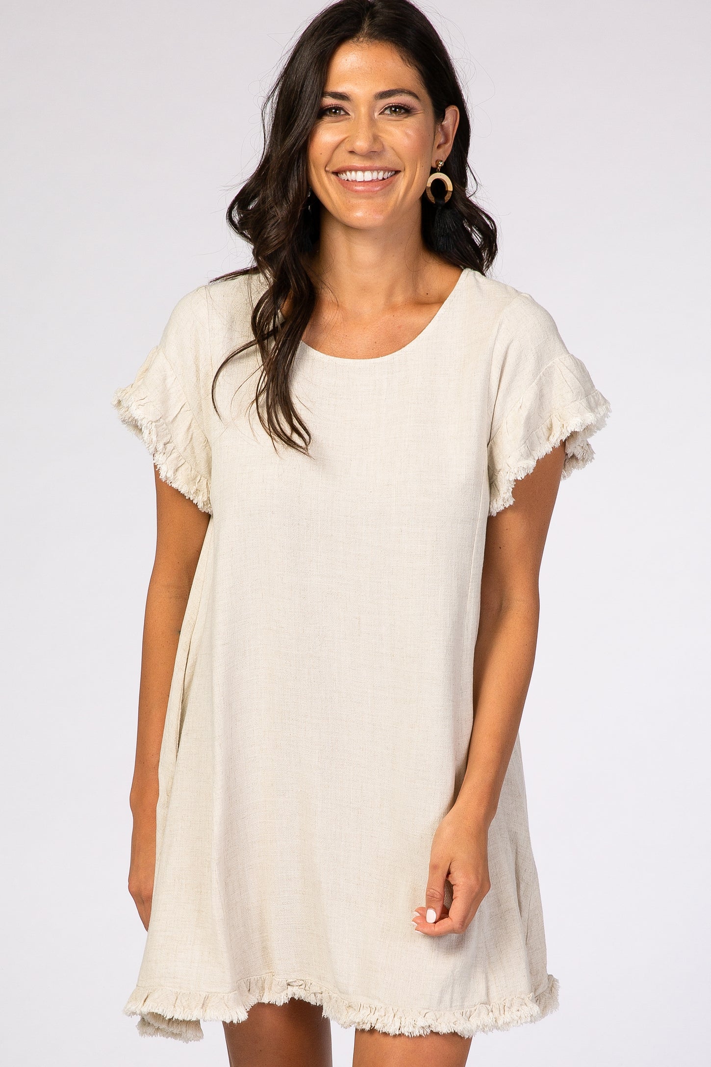 woman wearing a beige short sleeve linen dress with frayed edges and a relaxed fit