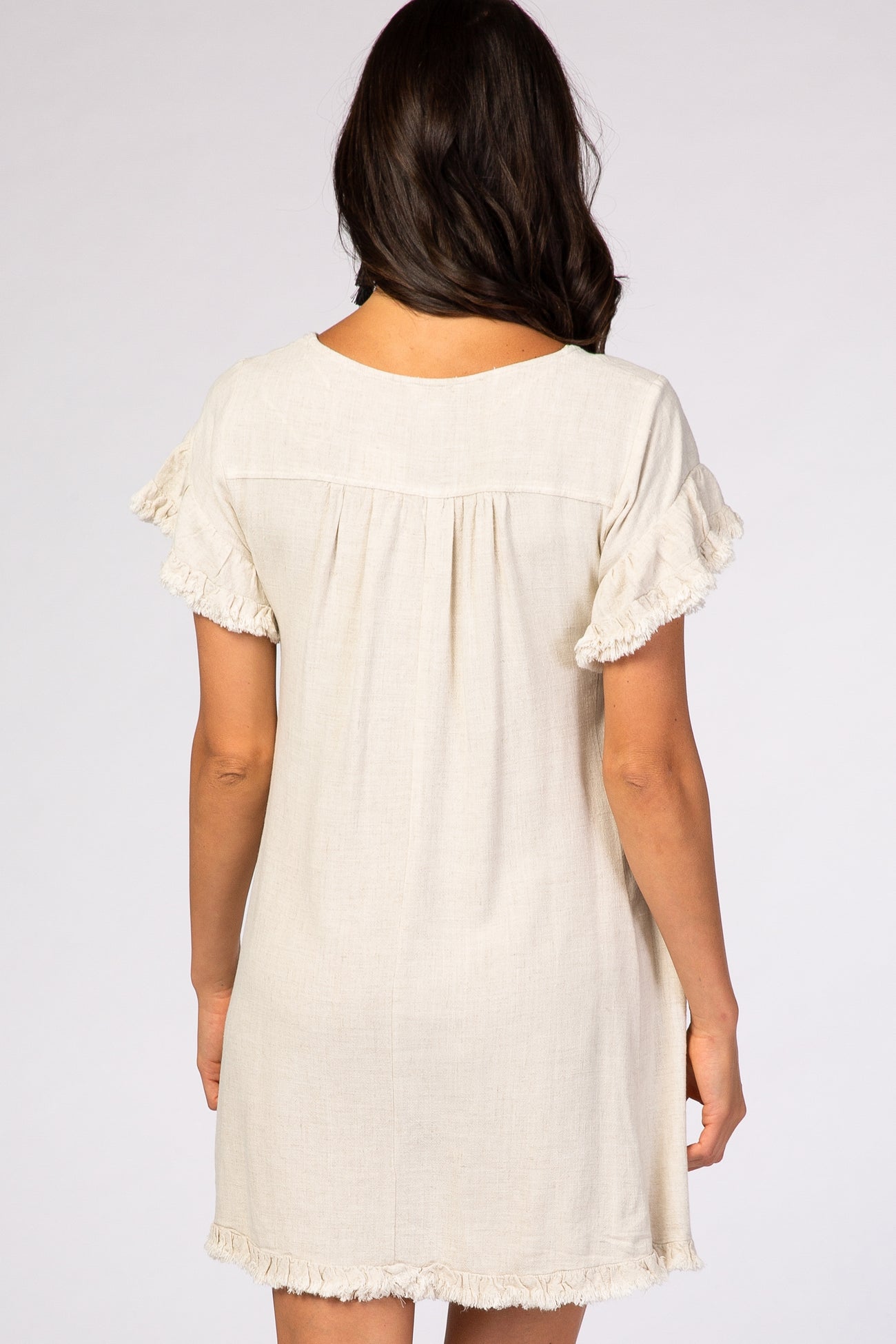 woman wearing a beige short-sleeve linen dress with ruffled sleeves and a relaxed fit from the back