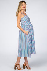 woman wearing a blue and multicolored striped maternity dress with pockets and a visible baby bump